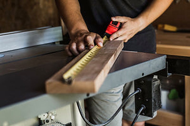 Carpenter measuring and marking a length of timber on a work bench